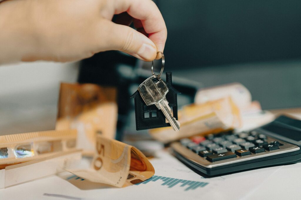 A person holding a house key in front of a calculator